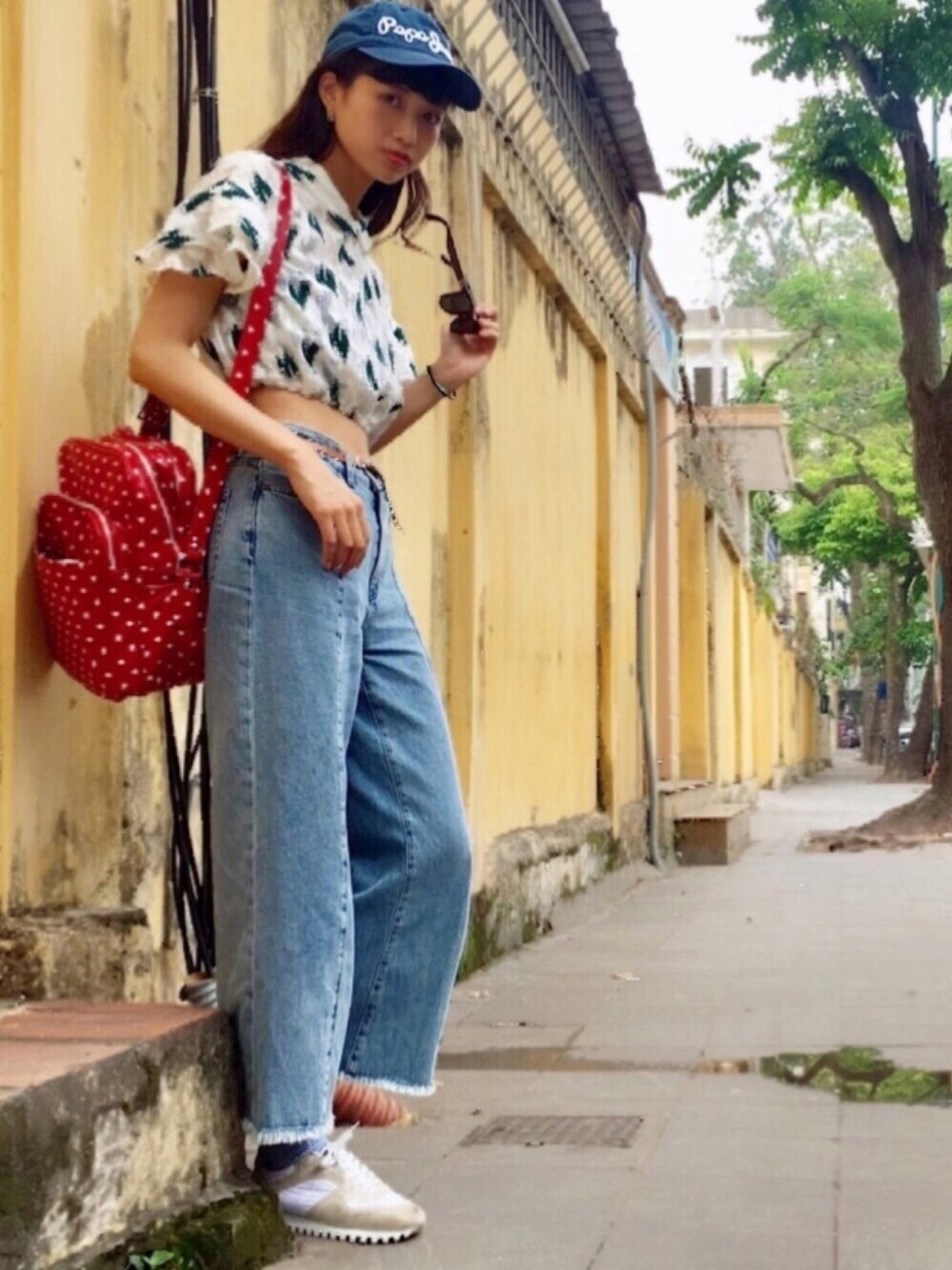 レッド系のボストンバッグ、ブルー系のデニムパンツ、ホワイト系のスニーカーを着用したレディースの夏コーディネートの1枚目の写真