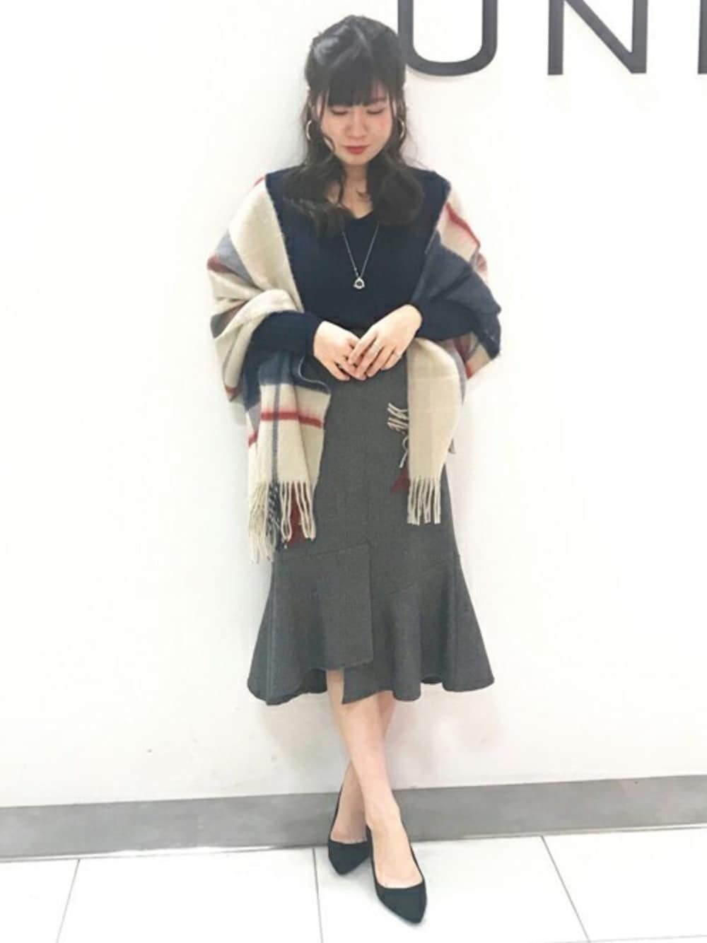 ブルー系のニット/セーター、グレー系のスカート、ブラック系のパンプスを着用したレディースの秋コーディネートの1枚目の写真