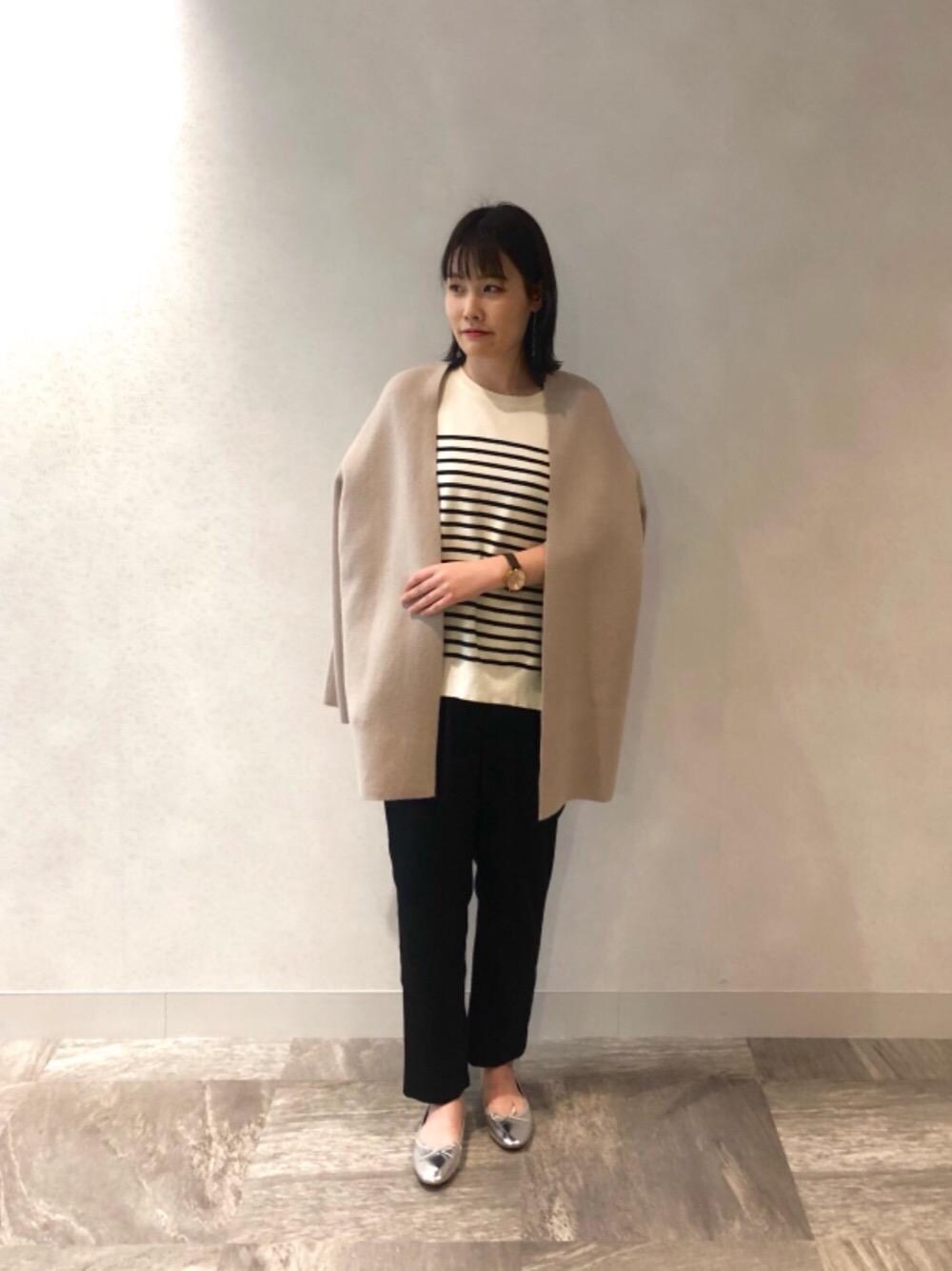 シルバー系のバレエシューズ、ベージュ系のカーディガン/ボレロ、ホワイト系のニット/セーターを着用したレディースの冬コーディネートの1枚目の写真