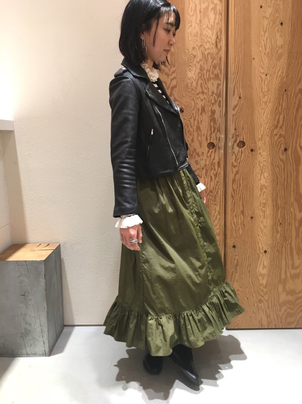 ブラック系のライダースジャケット、その他のニット/セーター、グリーン系のスカートを着用したレディースの冬コーディネートの1枚目の写真