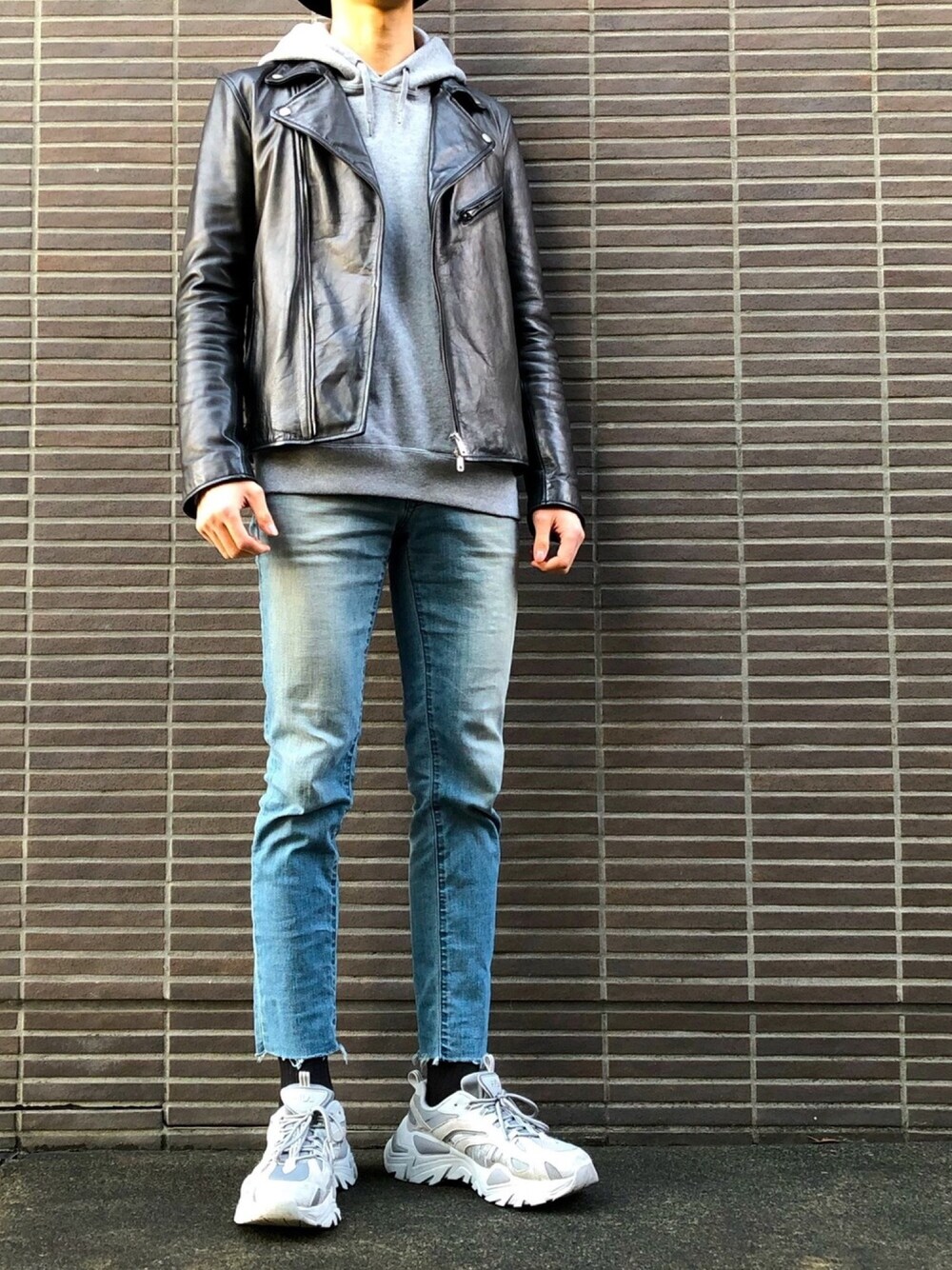 ブルー系のデニムパンツ、ブラック系のライダースジャケット、グレー系のスニーカーを着用したメンズの春コーディネートの1枚目の写真
