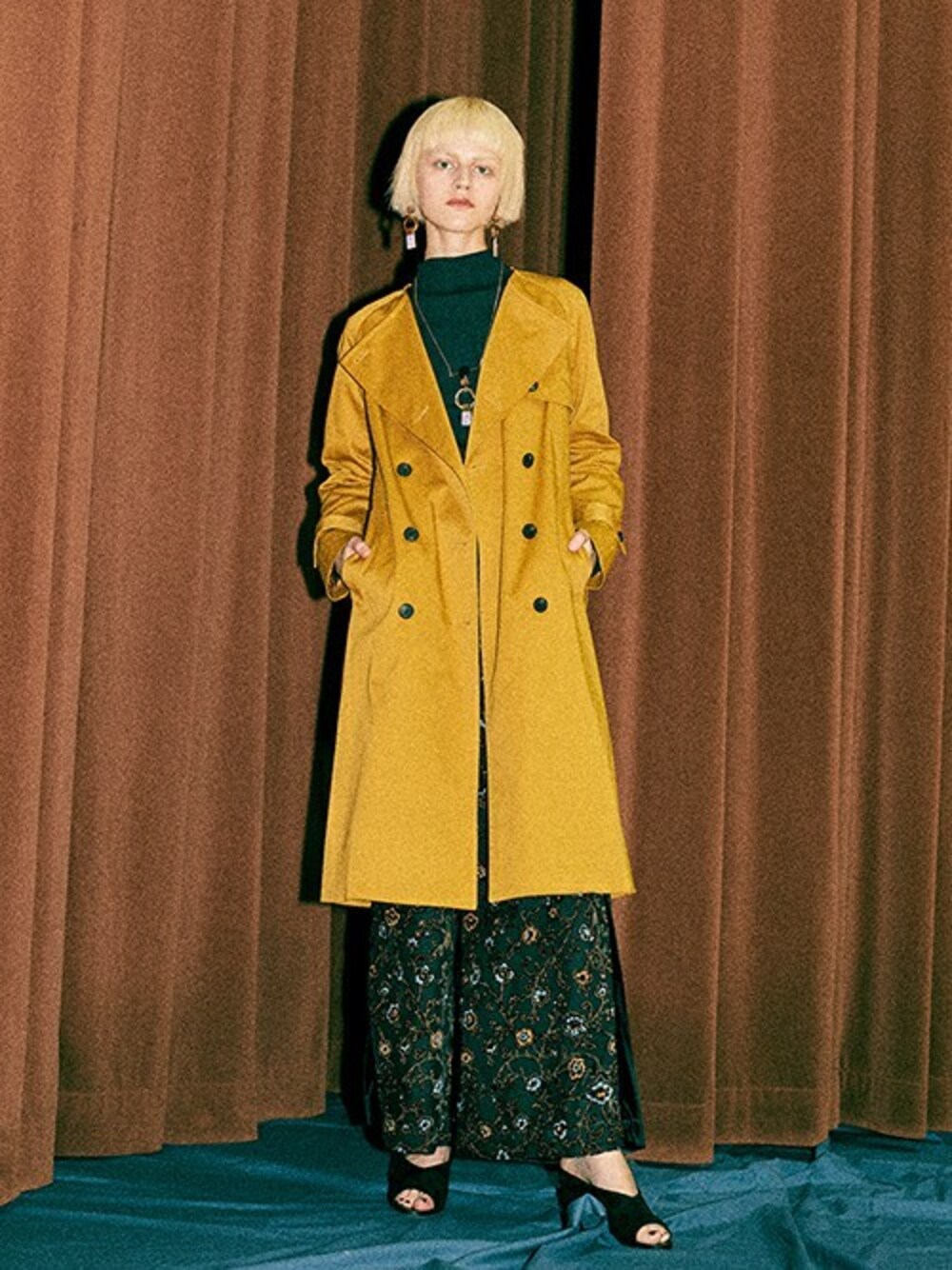 イエロー系のトレンチコート、ブラック系のTシャツ/カットソー、ブラック系のその他パンツを着用したレディースの秋コーディネートの1枚目の写真