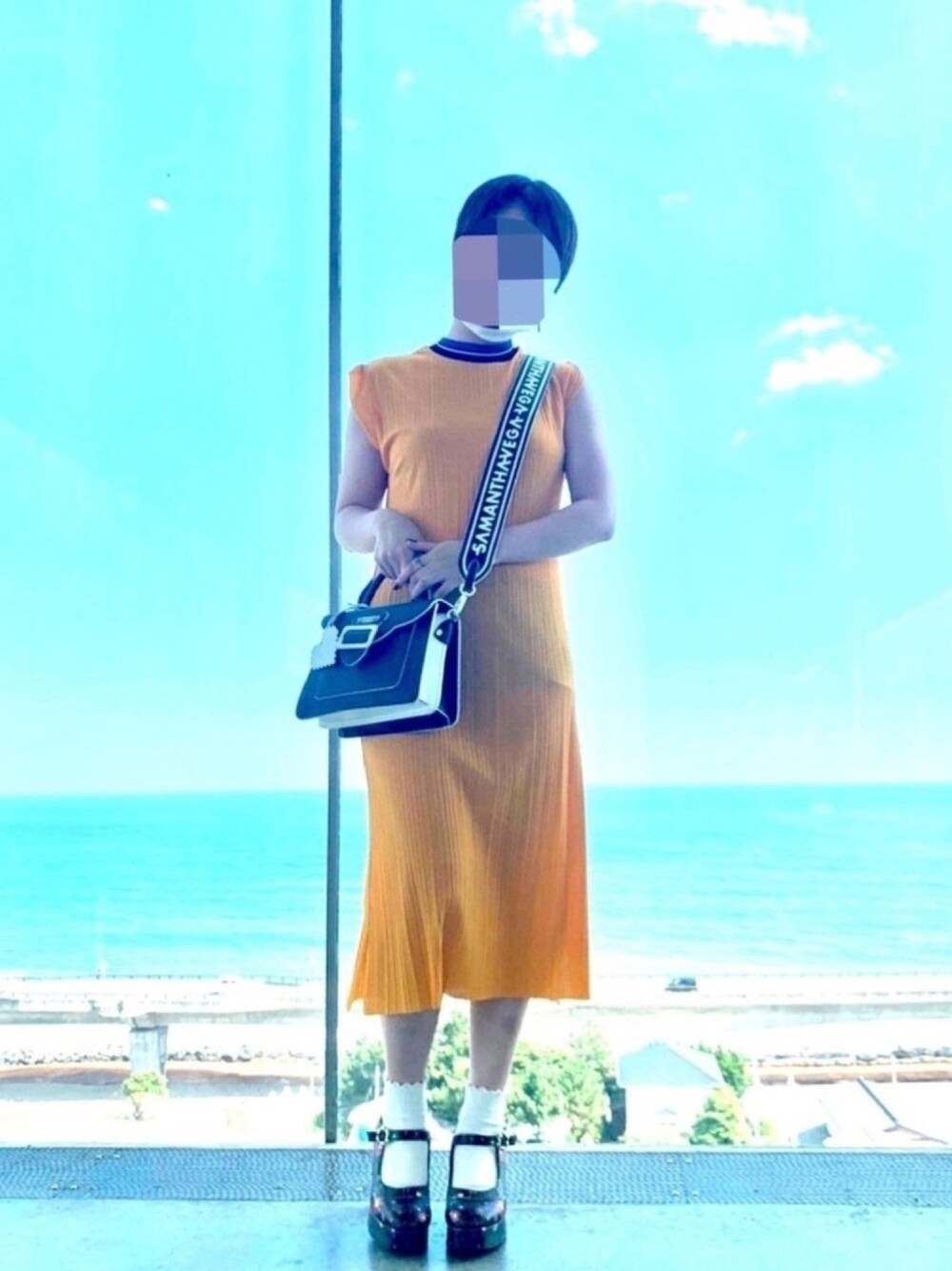 イエロー系のワンピース/ドレス、ブラック系のハンドバッグ、ブラック系のパンプスを着用したレディースの秋コーディネートの1枚目の写真