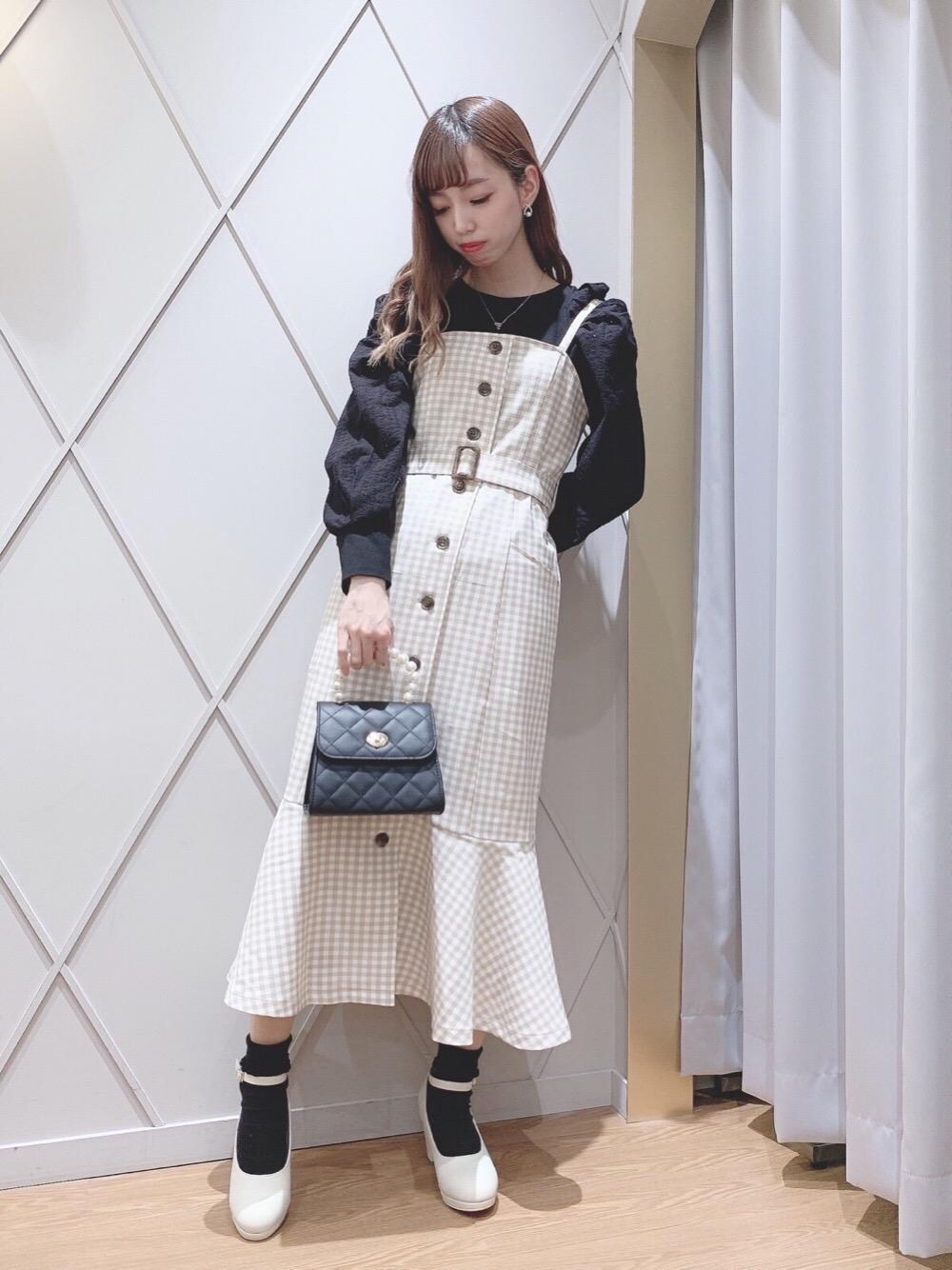 ホワイト系のパンプス、ブラック系のハンドバッグ、ベージュ系のワンピースを着用したレディースの冬コーディネートの1枚目の写真