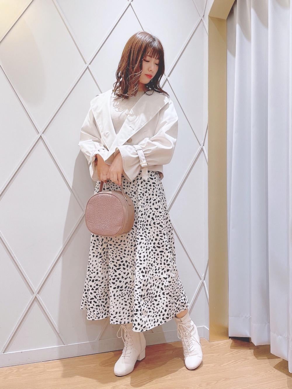 ホワイト系のブーツ、ピンク系のハンドバッグ、ホワイト系のトレンチコートを着用したレディースの冬コーディネートの1枚目の写真