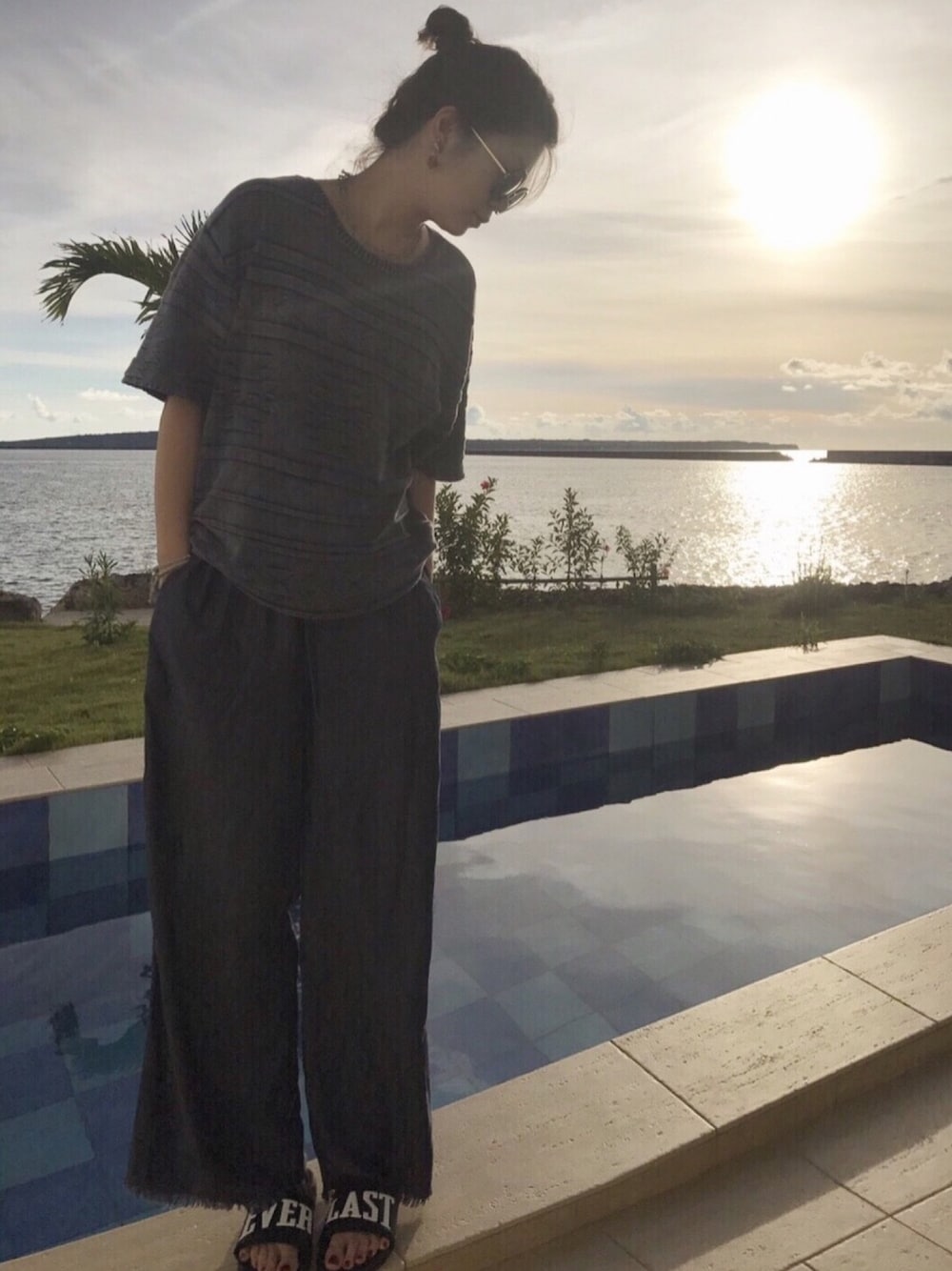 ブルー系のデニムパンツ、ブラック系のサンダル、ブルー系のニット/セーターを着用したレディースの夏コーディネートの1枚目の写真