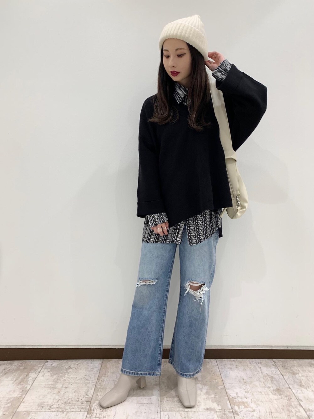 ブラック系のニット/セーター、ブラック系のシャツ/ブラウス、ブルー系のデニムパンツを着用したレディースの秋コーディネートの1枚目の写真