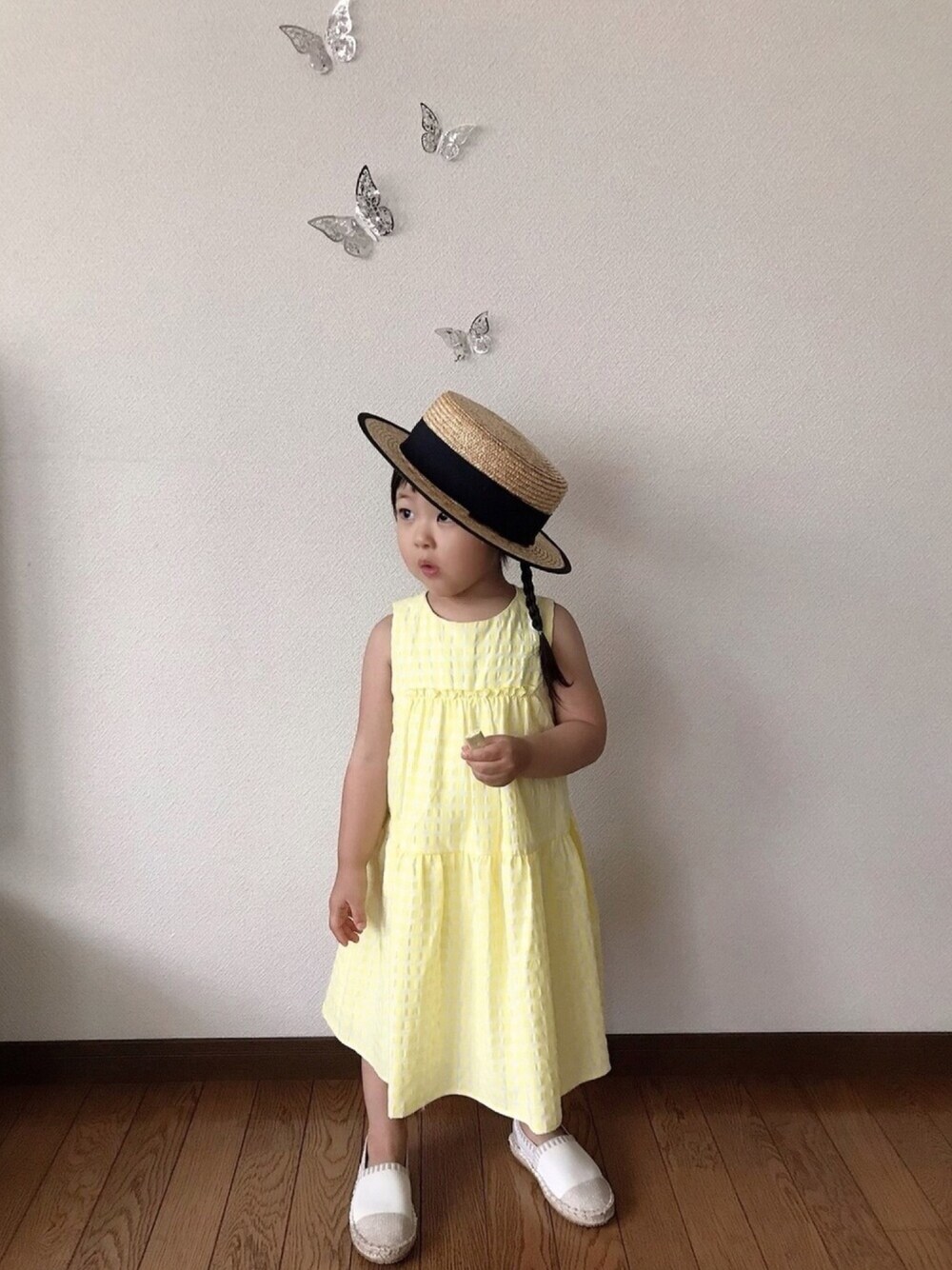 イエロー系のワンピース、ホワイト系のスリッポン、ブラウン系のハットを着用したキッズの夏コーディネートの1枚目の写真