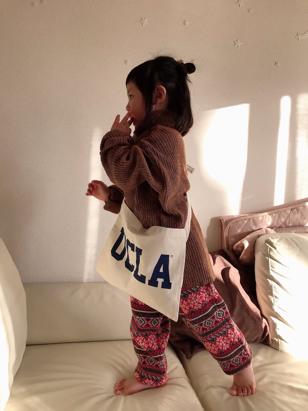 ブラウン系のニット/セーター、その他のその他パンツ、ホワイト系のショルダーバッグを着用したキッズの冬コーディネートの1枚目の写真