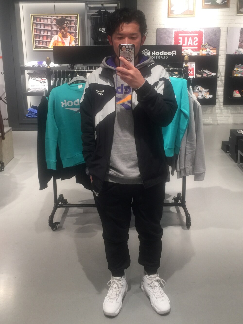 グレー系のパーカー、ブラック系のナイロンジャケット、ブラック系のその他パンツを着用したメンズの冬コーディネートの1枚目の写真