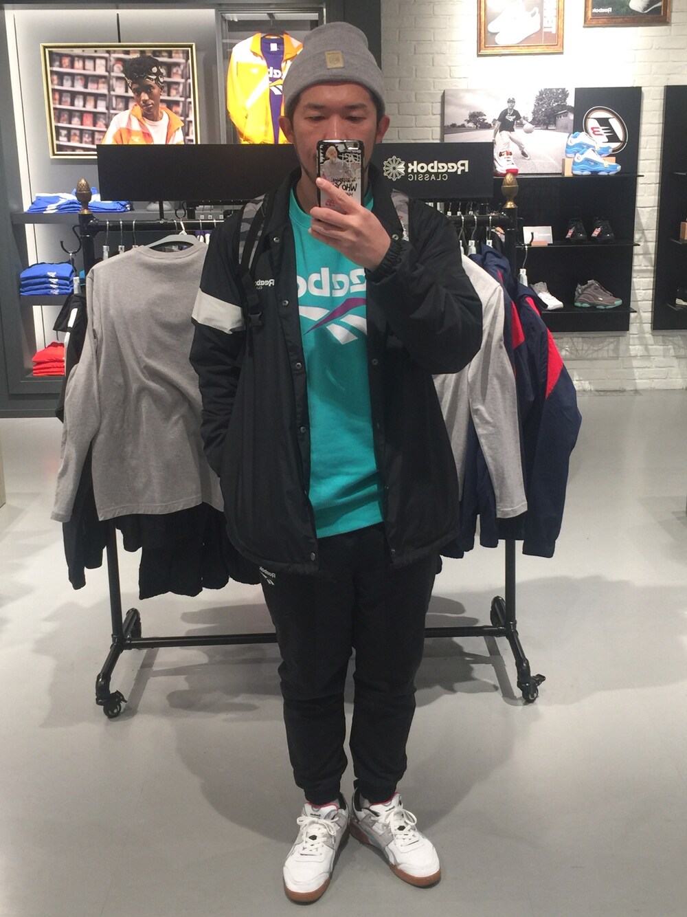 グリーン系のスウェット、ブラック系のナイロンジャケット、ブラック系のパンツを着用したメンズの冬コーディネートの1枚目の写真