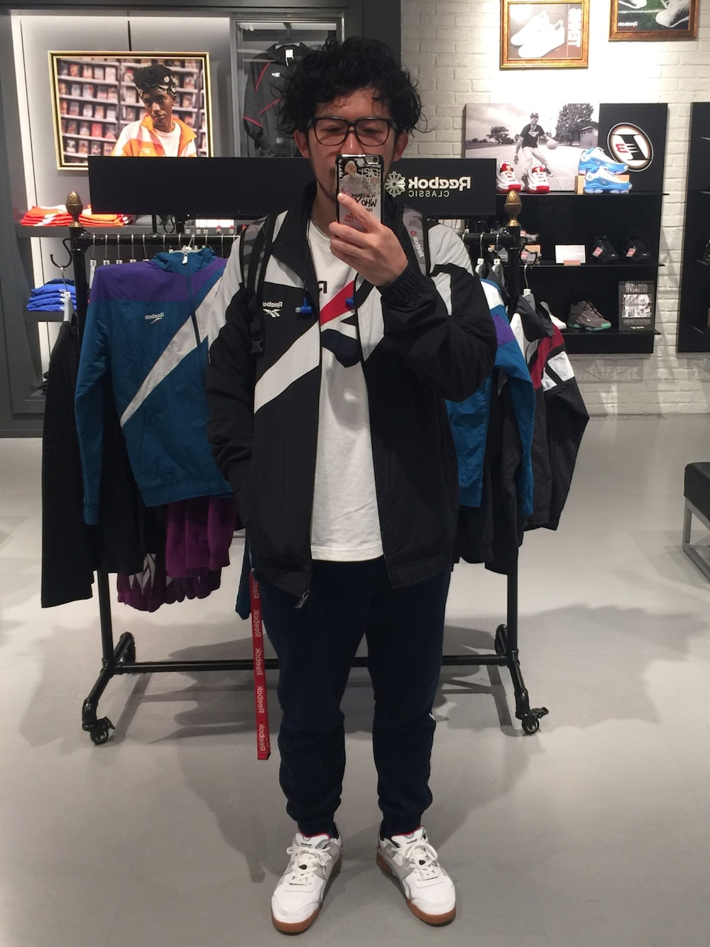 ブラック系のナイロンジャケット、ホワイト系のスニーカー、ブルー系のその他パンツを着用したメンズの春コーディネートの1枚目の写真