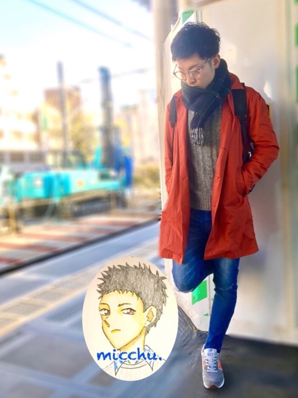 オレンジ系のステンカラーコート、グレー系のニット/セーター、ブルー系のデニムパンツを着用したメンズの冬コーディネートの1枚目の写真