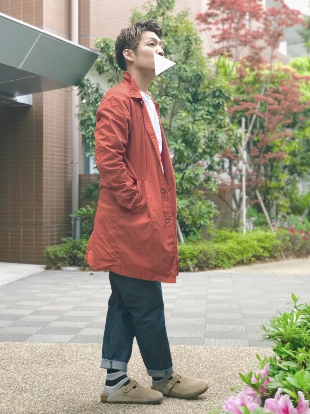 オレンジ系のステンカラーコート、ホワイト系のTシャツ/カットソー、ブルー系のデニムパンツを着用したメンズの春コーディネートの1枚目の写真