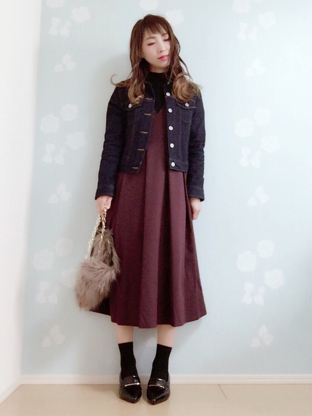 ブルー系のデニムジャケット、ブラック系のニット/セーター、レッド系のジャンパースカートを着用したレディースの冬コーディネートの1枚目の写真