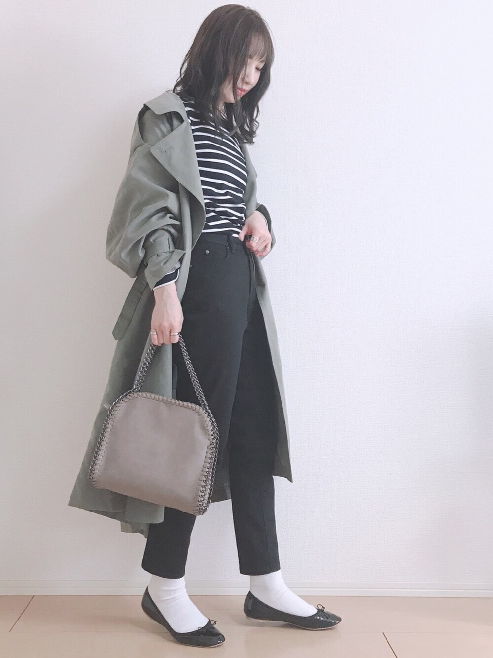 グリーン系のトレンチコート、ブルー系のTシャツ/カットソー、ブラック系のデニムパンツを着用したレディースの冬コーディネートの1枚目の写真