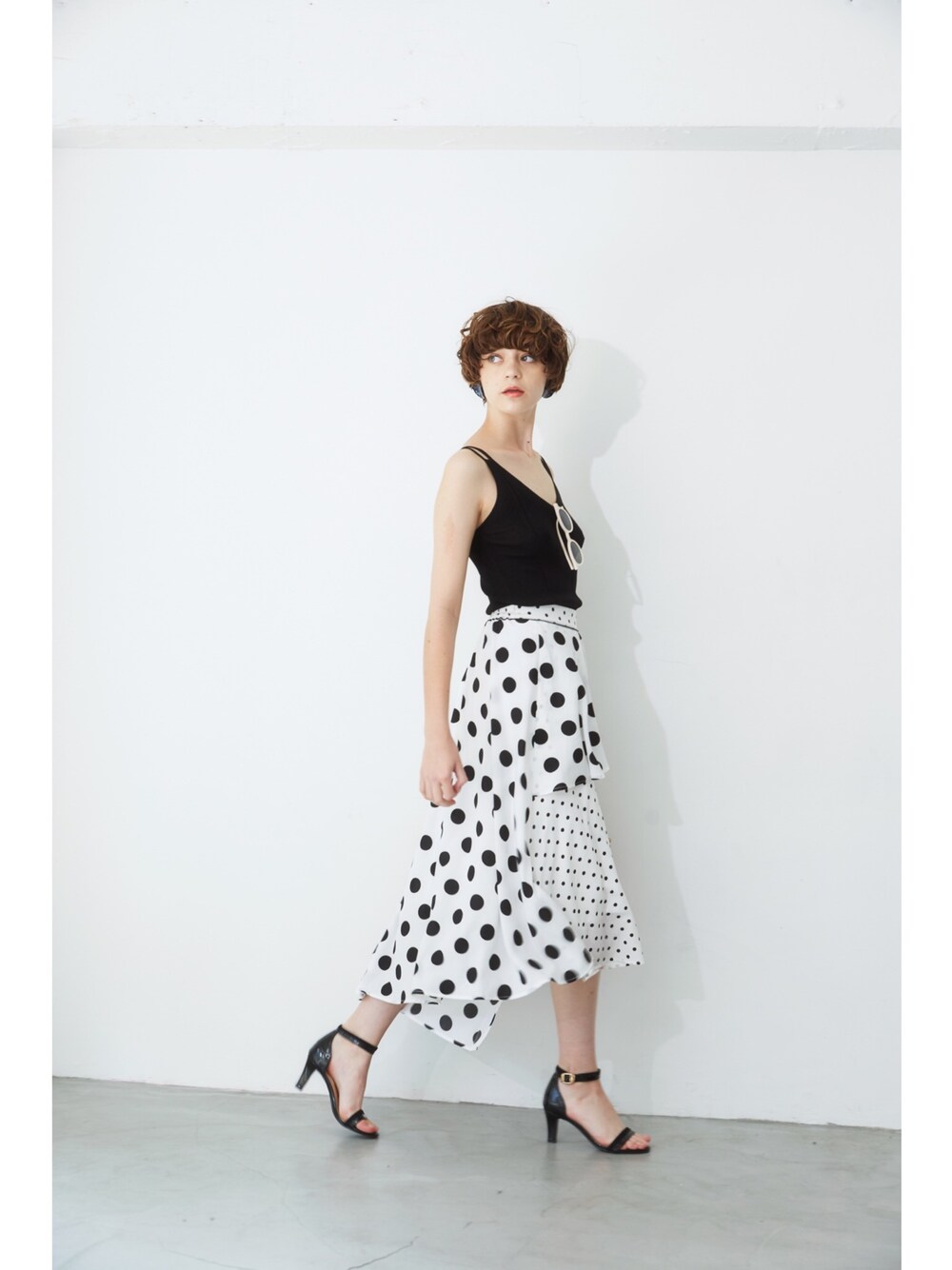 ブラック系のキャミソール、ホワイト系のスカートを着用したレディースの春コーディネートの1枚目の写真