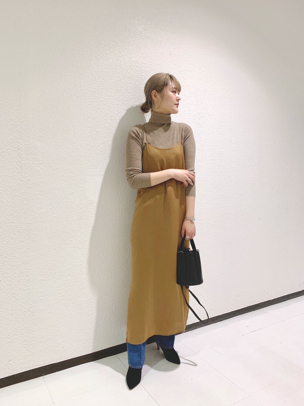イエロー系のワンピース、ブルー系のデニムパンツ、ベージュ系のニット/セーターを着用したレディースの冬コーディネートの1枚目の写真