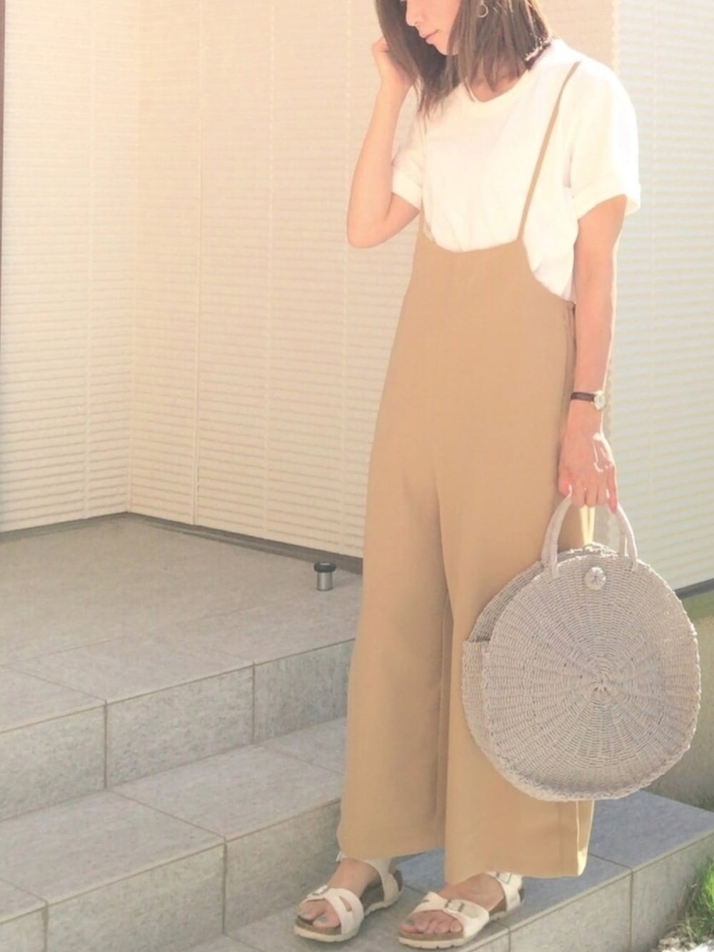 ベージュ系のサロペット/オーバーオール、グレー系のかごバッグ、ホワイト系のTシャツ/カットソーを着用したレディースの春コーディネートの1枚目の写真