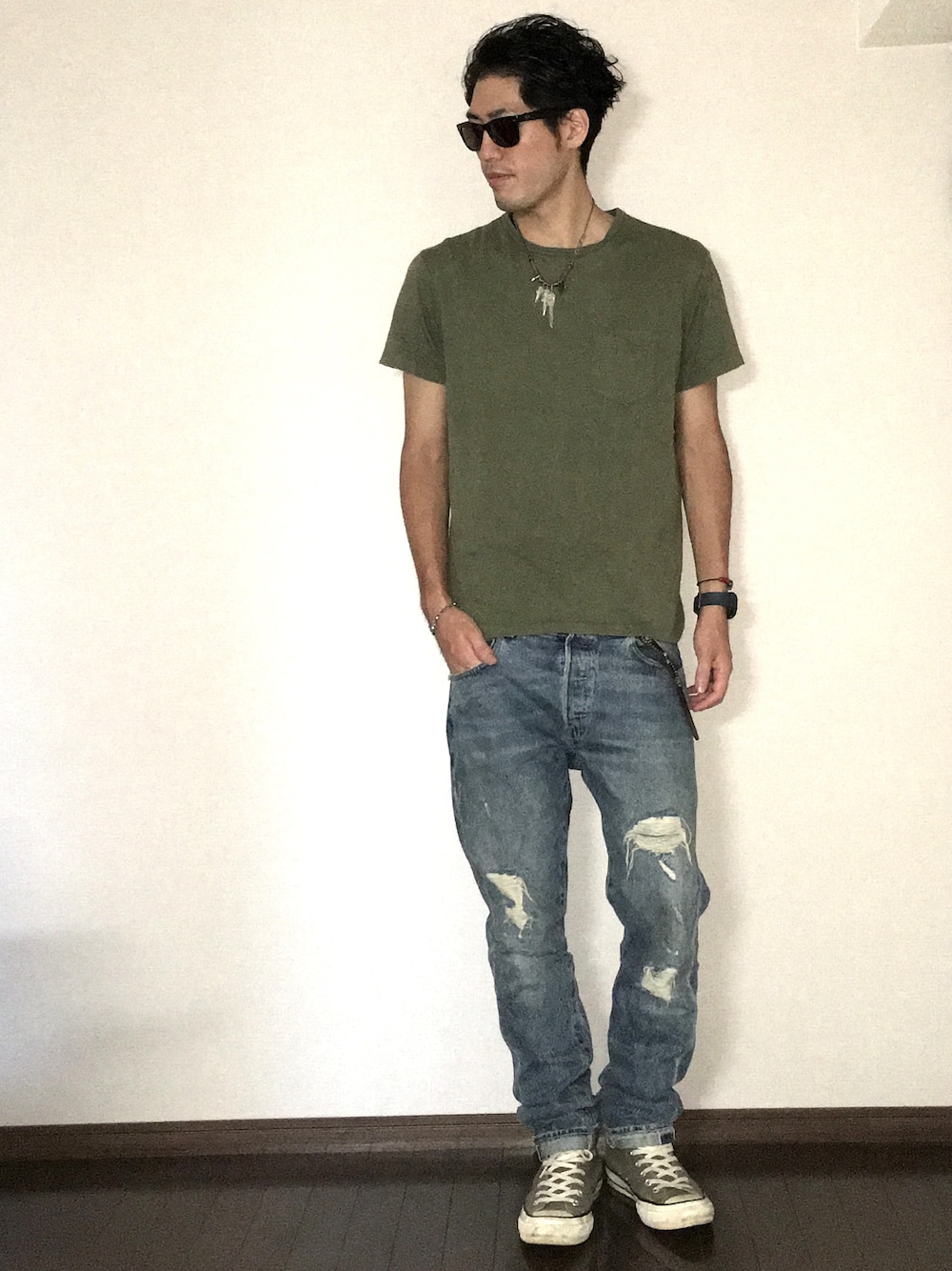 グリーン系のTシャツ/カットソー、ブルー系のデニムパンツ、グレー系のスニーカーを着用したメンズの秋コーディネートの1枚目の写真