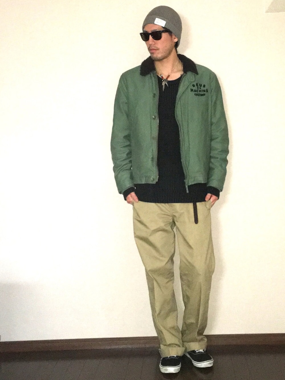 グリーン系のミリタリージャケット、ブラック系のニット/セーター、ブラック系のチノパンツを着用したメンズの秋コーディネートの1枚目の写真