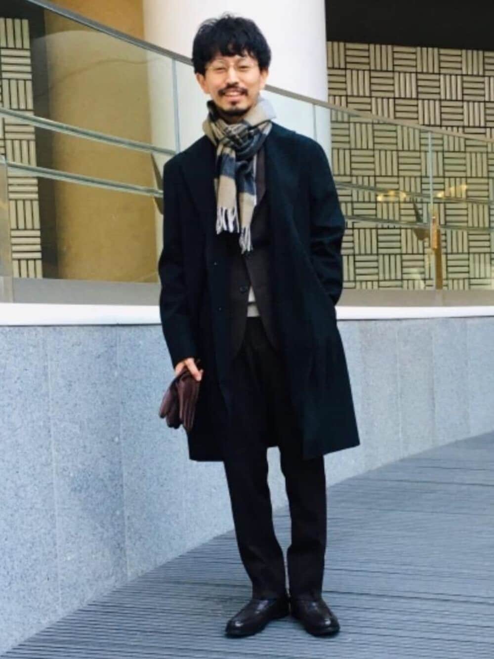 ブラウン系のローファー、ベージュ系のニット/セーター、グレー系のチェスターコートを着用したメンズの冬コーディネートの1枚目の写真