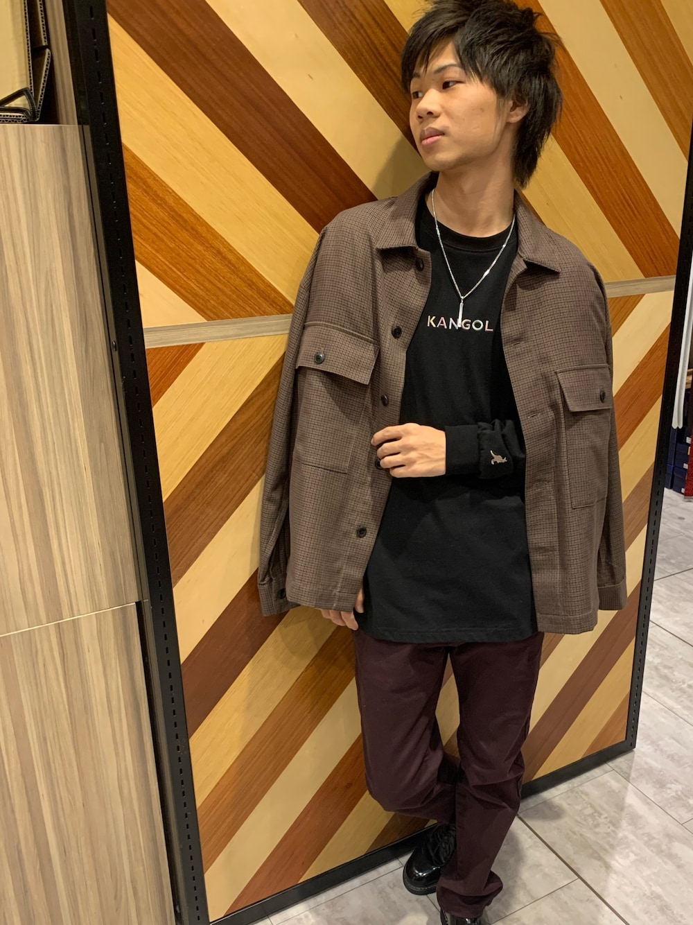 レッド系のチノパンツ、ブラック系のTシャツ/カットソー、ブラウン系のジャケット/アウターを着用したメンズの冬コーディネートの1枚目の写真