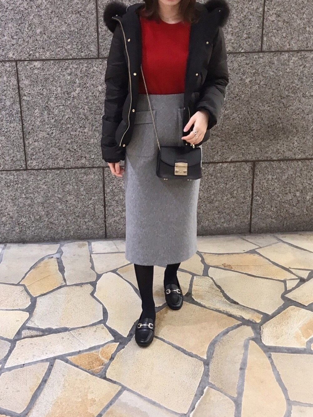 ブラック系のダウンジャケット/コート、レッド系のニット/セーター、グレー系のスカートを着用したレディースの冬コーディネートの1枚目の写真