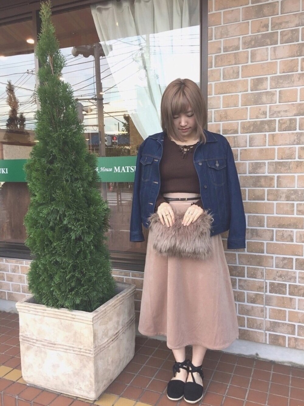 ベージュ系のクラッチバッグ、ブラウン系のニット/セーター、ブルー系のデニムジャケットを着用したレディースの秋コーディネートの1枚目の写真