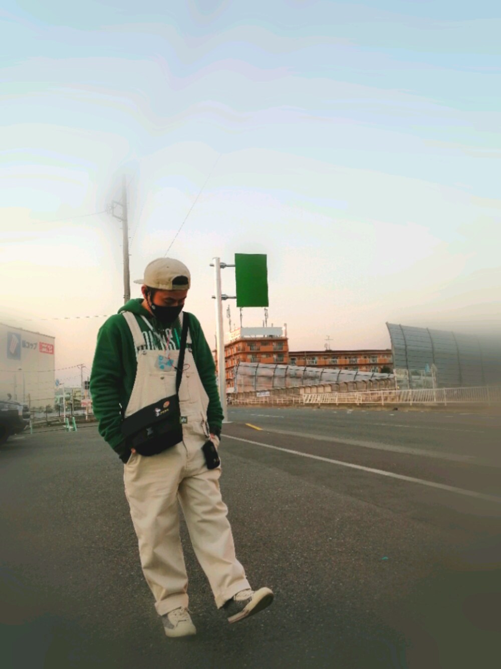 グリーン系のパーカー、ベージュ系のサロペット/オーバーオール、ブラック系のバッグを着用したメンズの冬コーディネートの1枚目の写真