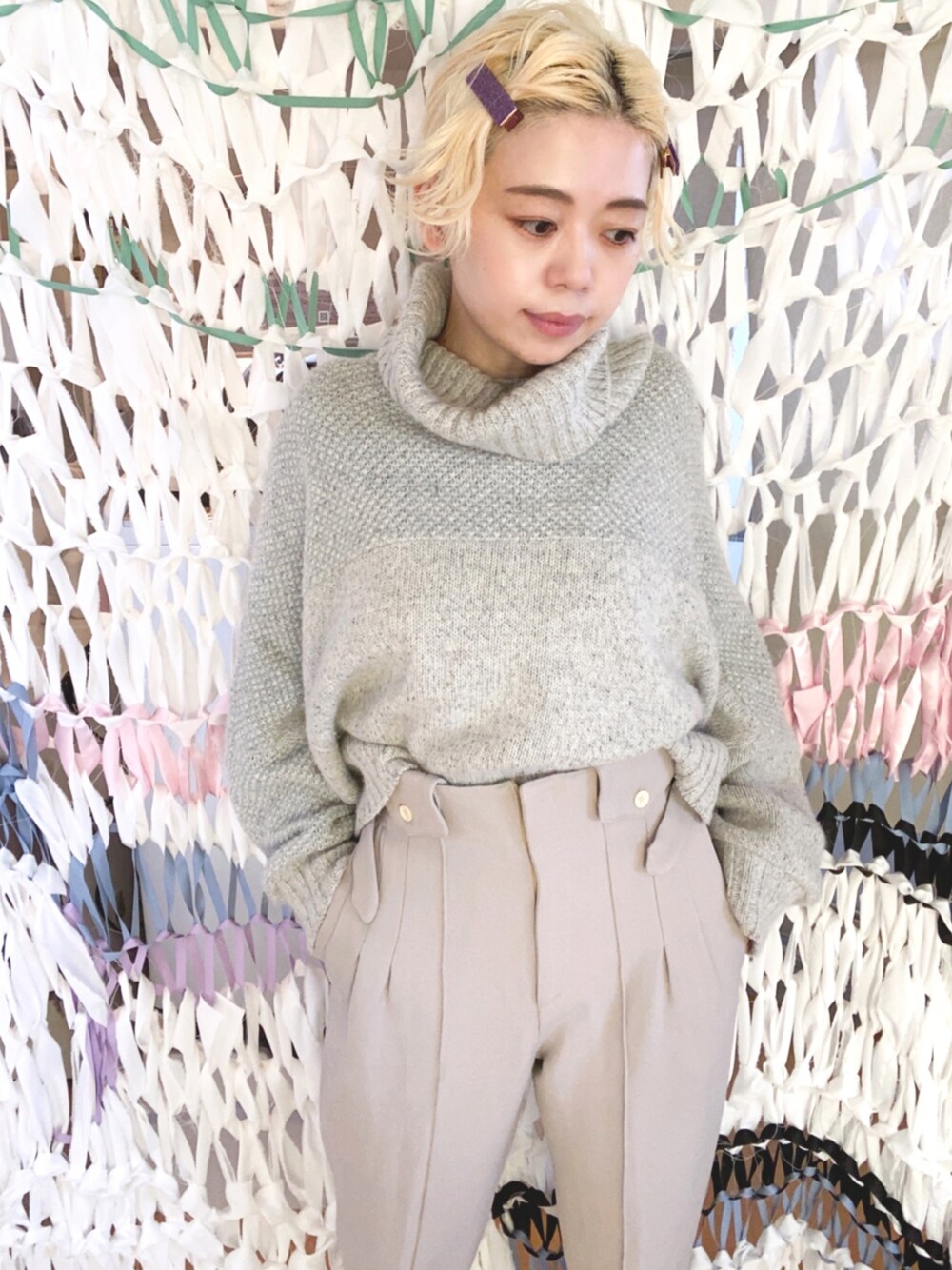 グレー系のニット/セーター、グレー系のパンツ、パープル系のバレッタ/ヘアクリップを着用したレディースの秋コーディネートの1枚目の写真