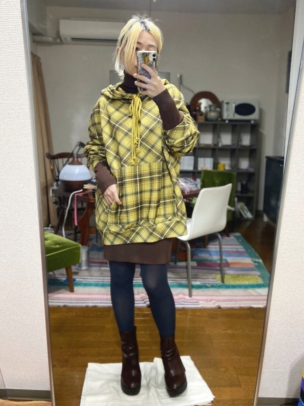 イエロー系のパーカー、ブラウン系のワンピース、ブラウン系のブーツを着用したレディースの冬コーディネートの1枚目の写真