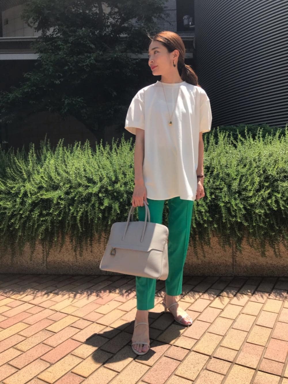 グレー系のビジネスバッグ、グリーン系のその他パンツ、ベージュ系のサンダルを着用したレディースの春コーディネートの1枚目の写真