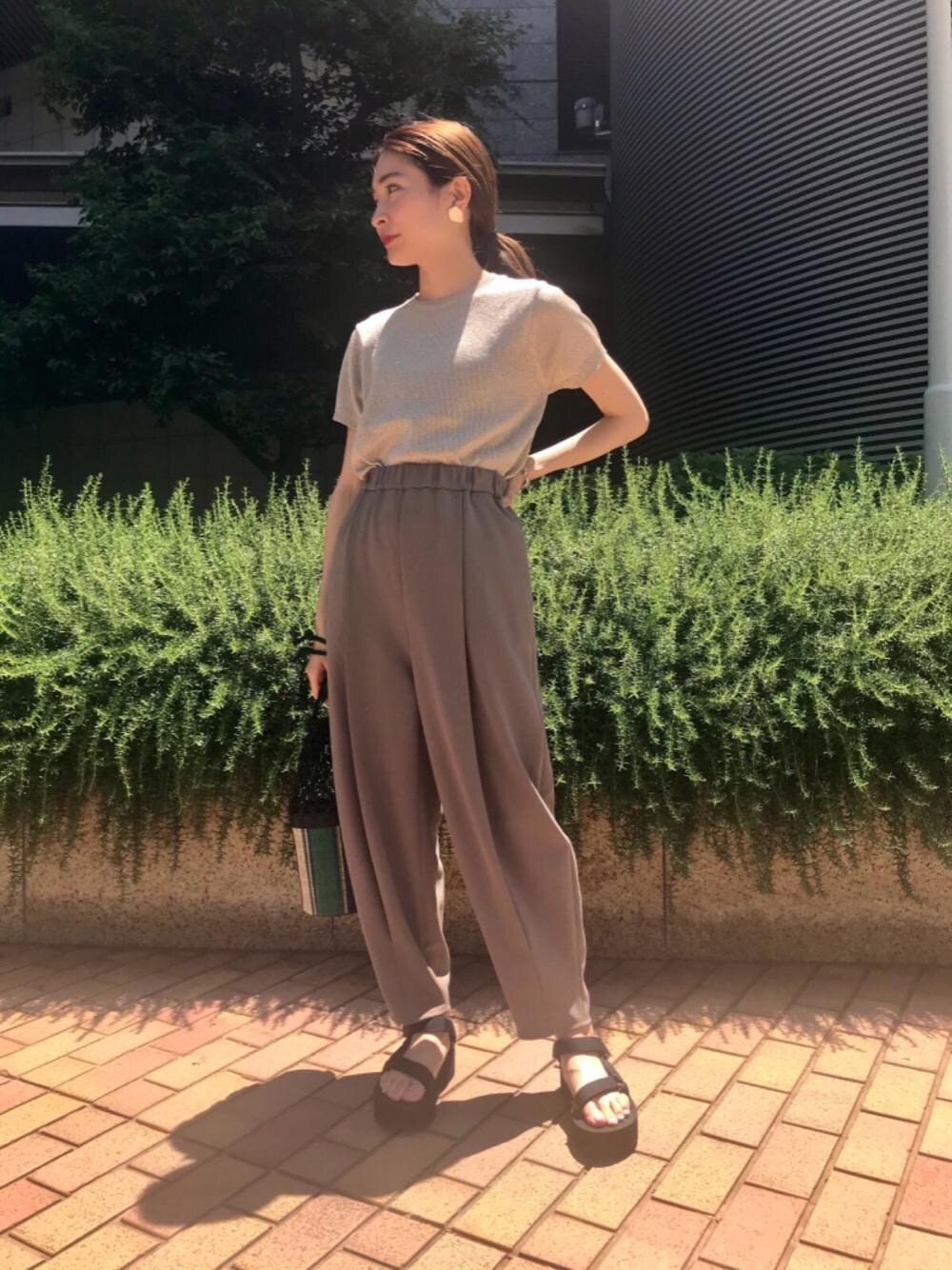 ゴールド系のニット/セーター、ブラック系のサンダル、ブルー系のハンドバッグを着用したレディースの春コーディネートの1枚目の写真