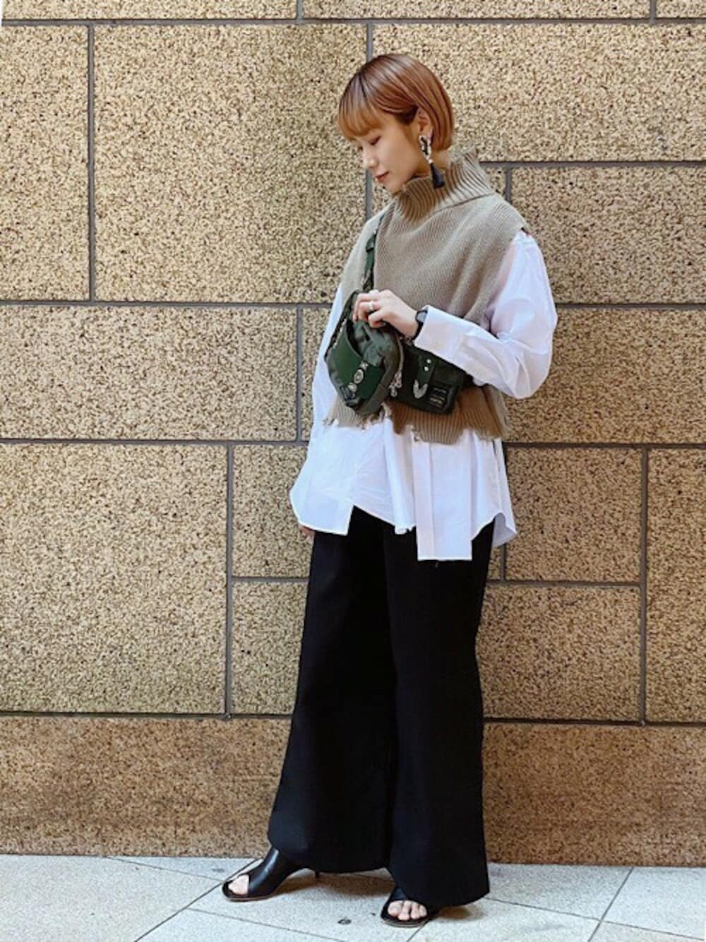 ベージュ系のベスト、ブラック系のイヤリングを着用したレディースの春コーディネートの1枚目の写真