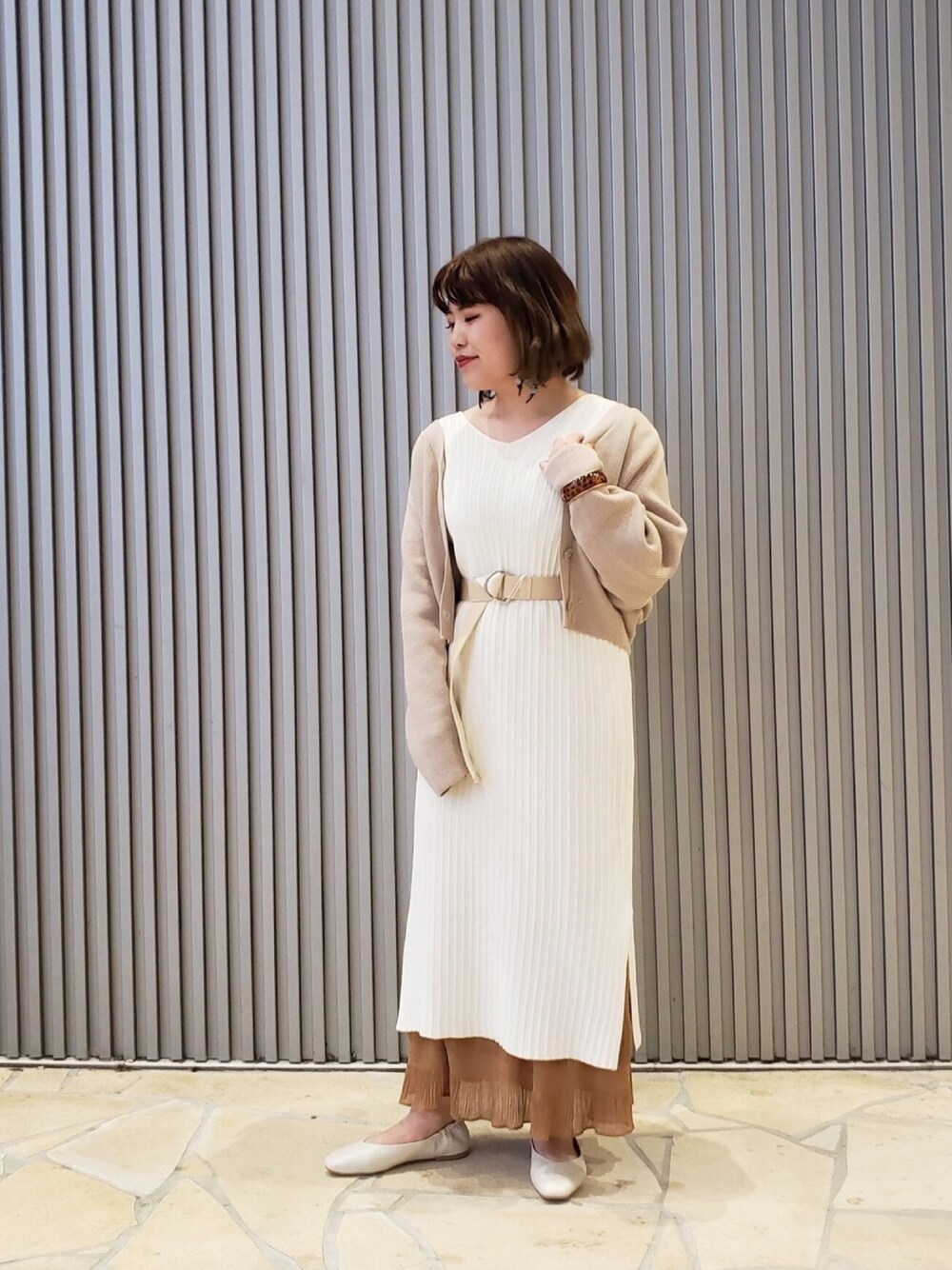 ベージュ系のカーディガン/ボレロ、ホワイト系のワンピース、ブラウン系のスカートを着用したレディースの冬コーディネートの1枚目の写真