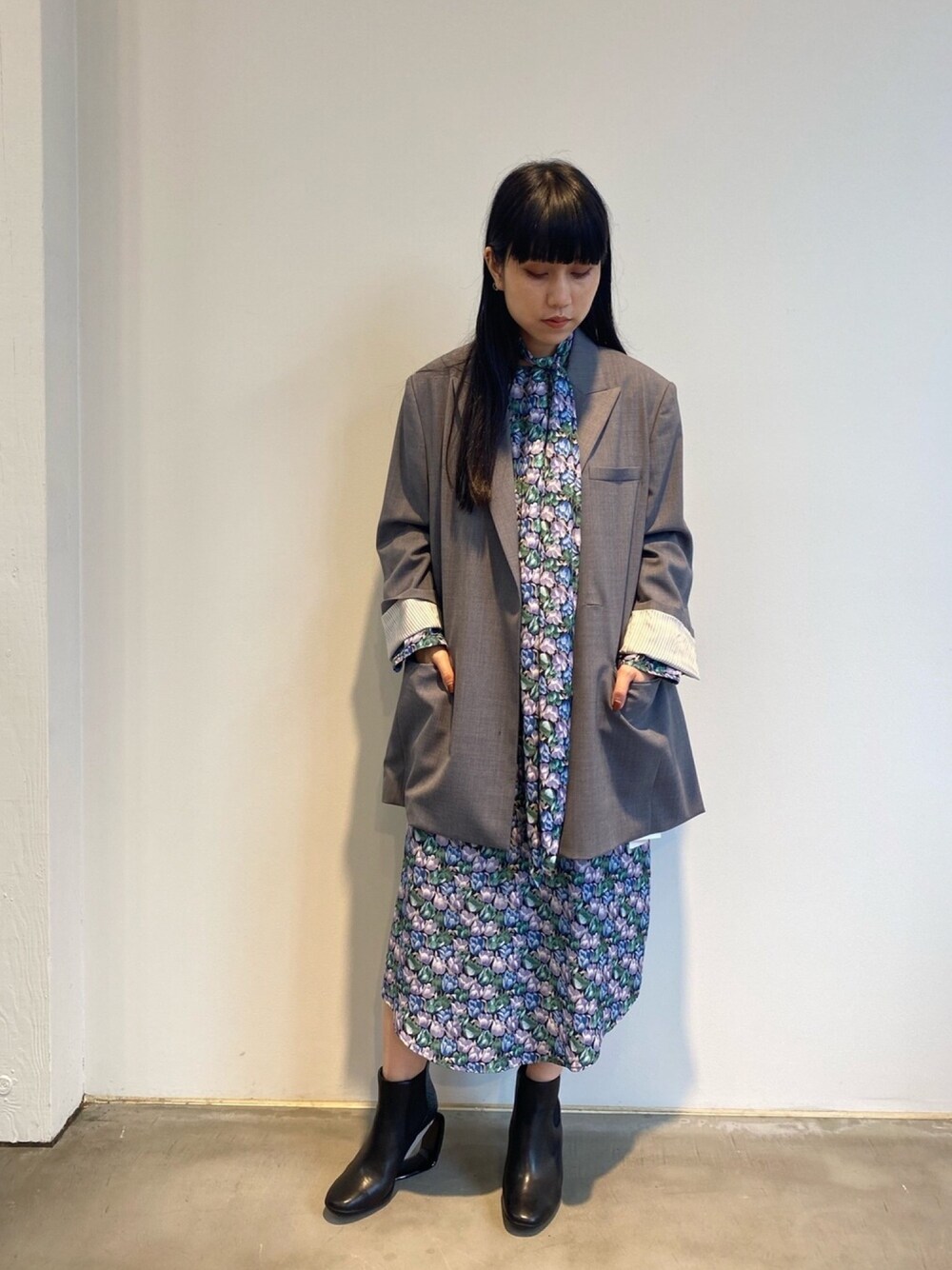 ブラック系のブーツ、グレー系のテーラードジャケット、ブルー系のワンピースを着用したレディースの秋コーディネートの1枚目の写真