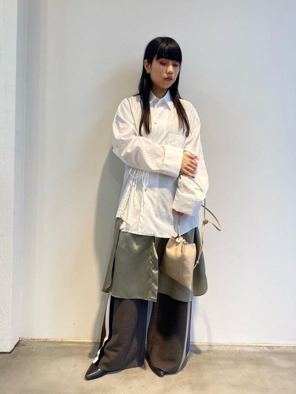 ベージュ系のショルダーバッグ、ホワイト系のワンピース、ブラウン系のパンツを着用したレディースの秋コーディネートの1枚目の写真