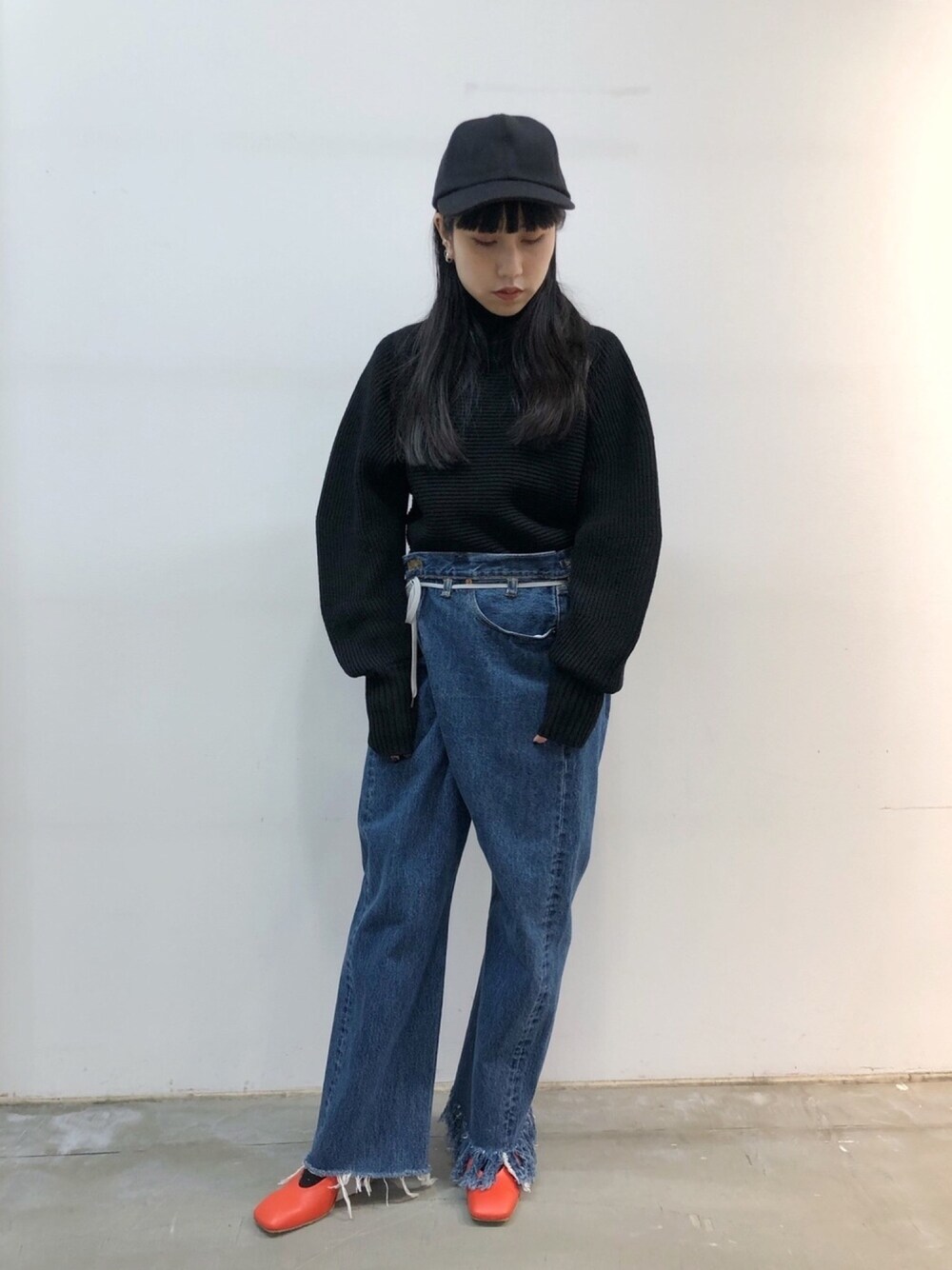 ブルー系のデニムパンツ、ブラック系のニット/セーター、オレンジ系のパンプスを着用したレディースの冬コーディネートの1枚目の写真