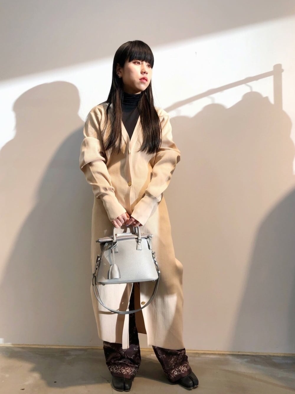 ベージュ系のワンピース、グレー系のハンドバッグ、ブラウン系のその他パンツを着用したレディースの冬コーディネートの1枚目の写真