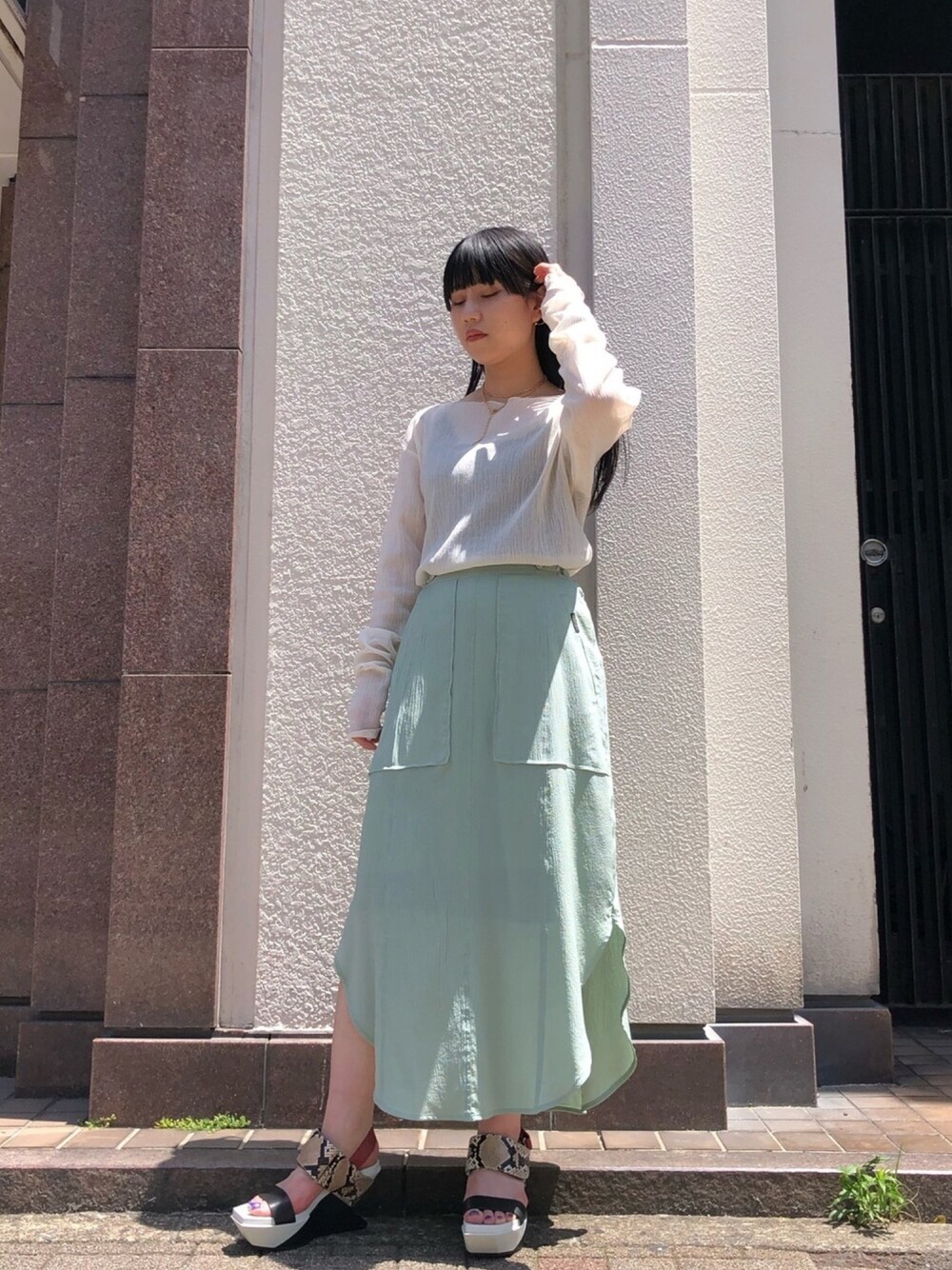 グリーン系のスカート、その他のサンダル、ホワイト系のトップスを着用したレディースの春コーディネートの1枚目の写真