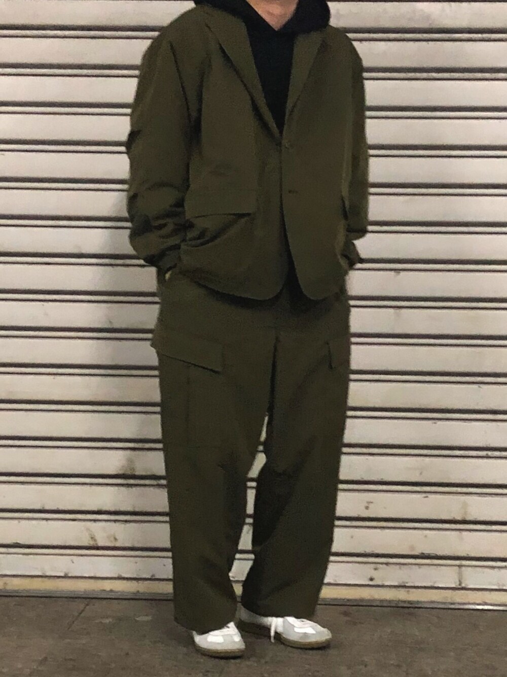 グリーン系のカーゴパンツ、グリーン系のジャケット/アウター、ホワイト系のスニーカーを着用したメンズの春コーディネートの1枚目の写真