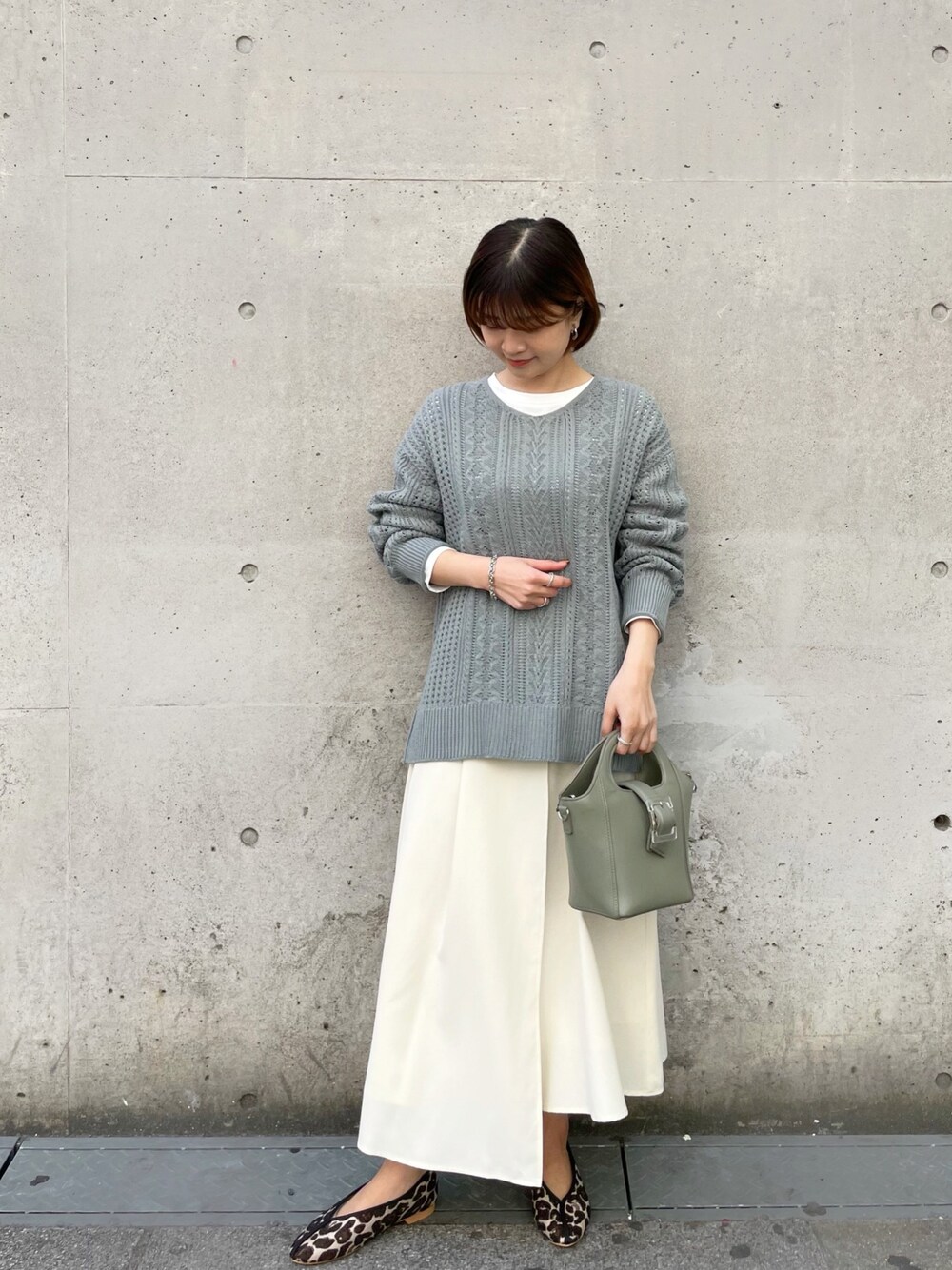 ホワイト系のTシャツ/カットソー、グリーン系のニット/セーター、ホワイト系のスカートを着用したレディースの春コーディネートの1枚目の写真