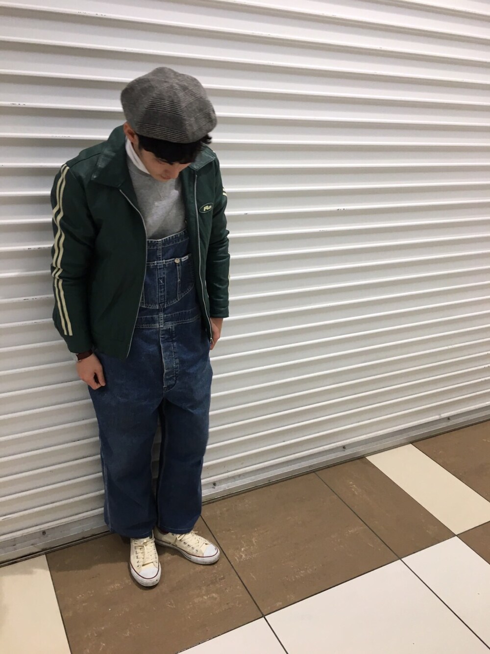 グレー系のスウェット、グリーン系のライダースジャケット、ブルー系のサロペット/オーバーオールを着用したメンズの冬コーディネートの1枚目の写真