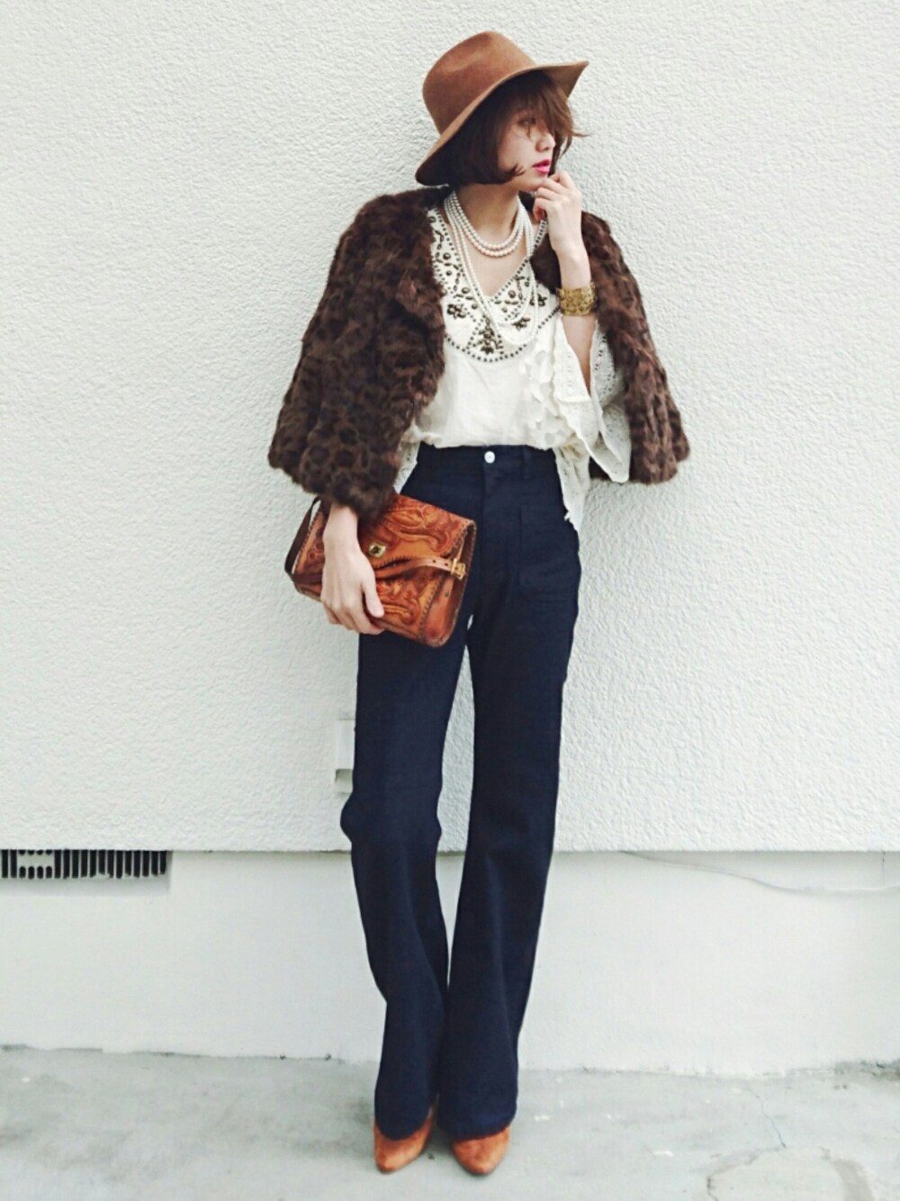 ブルー系のデニムパンツ、ブラウン系のパンプス、ブラウン系のバッグを着用したレディースの冬コーディネートの1枚目の写真