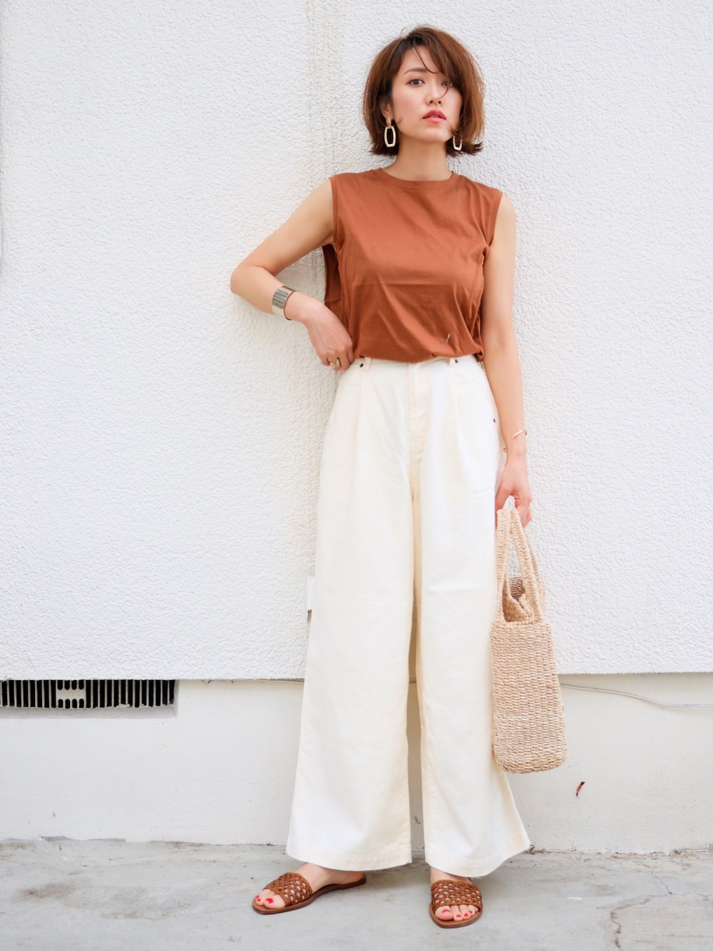 ベージュ系のその他パンツ、ブラウン系のサンダル、ベージュ系のかごバッグを着用したレディースの夏コーディネートの1枚目の写真