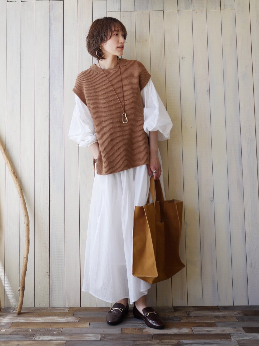 ホワイト系のワンピース、ブラウン系のトップス、ブラウン系のバッグを着用したレディースの春コーディネートの1枚目の写真