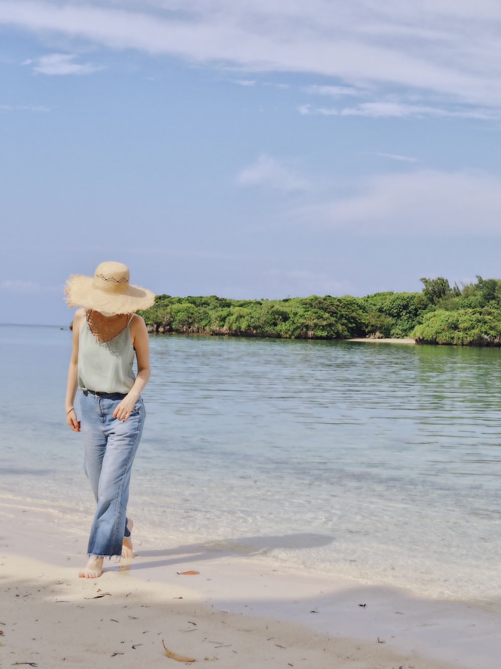 グリーン系のキャミソール、ベージュ系のハットを着用したレディースの秋コーディネートの1枚目の写真