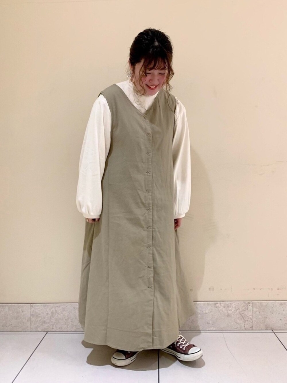 グリーン系のジャンパースカート、ホワイト系のTシャツ/カットソーを着用したレディースの冬コーディネートの1枚目の写真