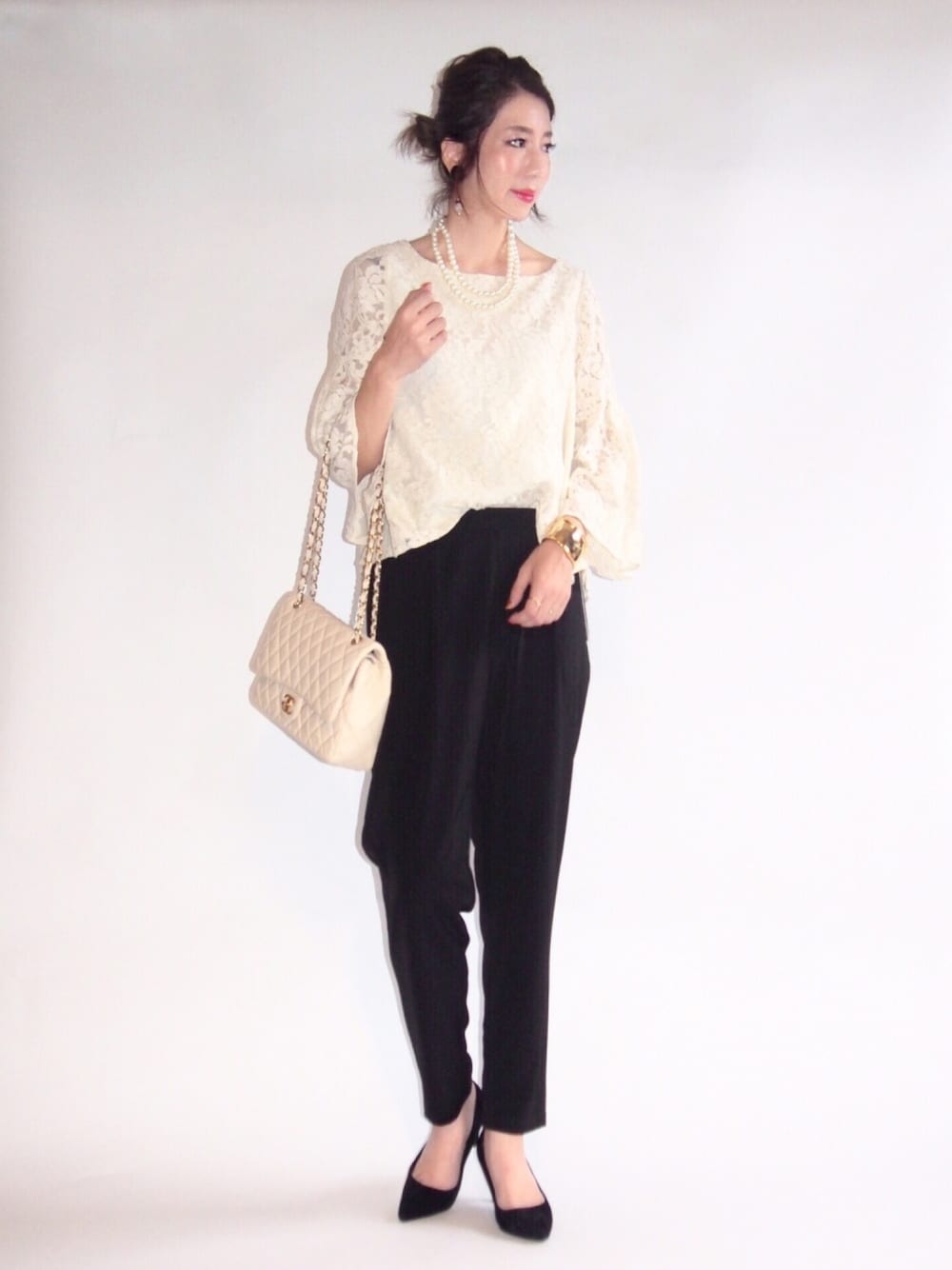 ブラック系のパンツドレス、ベージュ系のショルダーバッグ、ブラック系のパンプスを着用したレディースの秋コーディネートの1枚目の写真